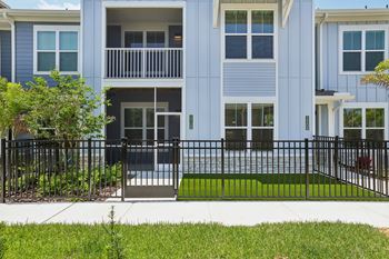 A blue building with a black fence and a green lawn in front. at The Junction at Rockledge Apartments, Rockledge 32955